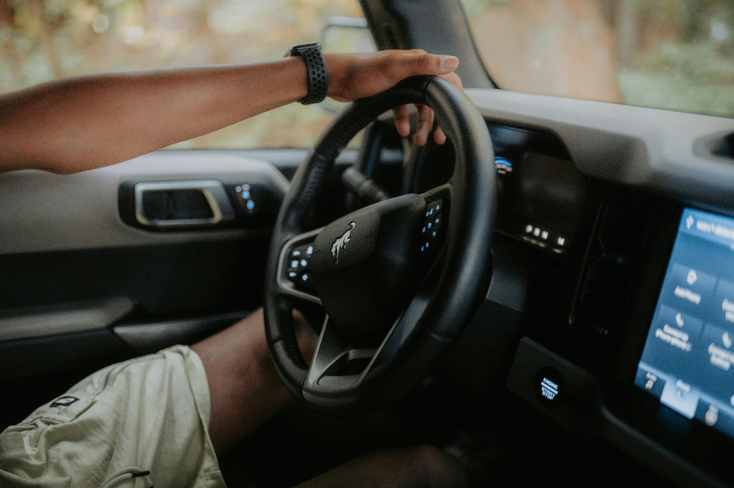 A person driving a modern car, focusing on hands and steering wheel.